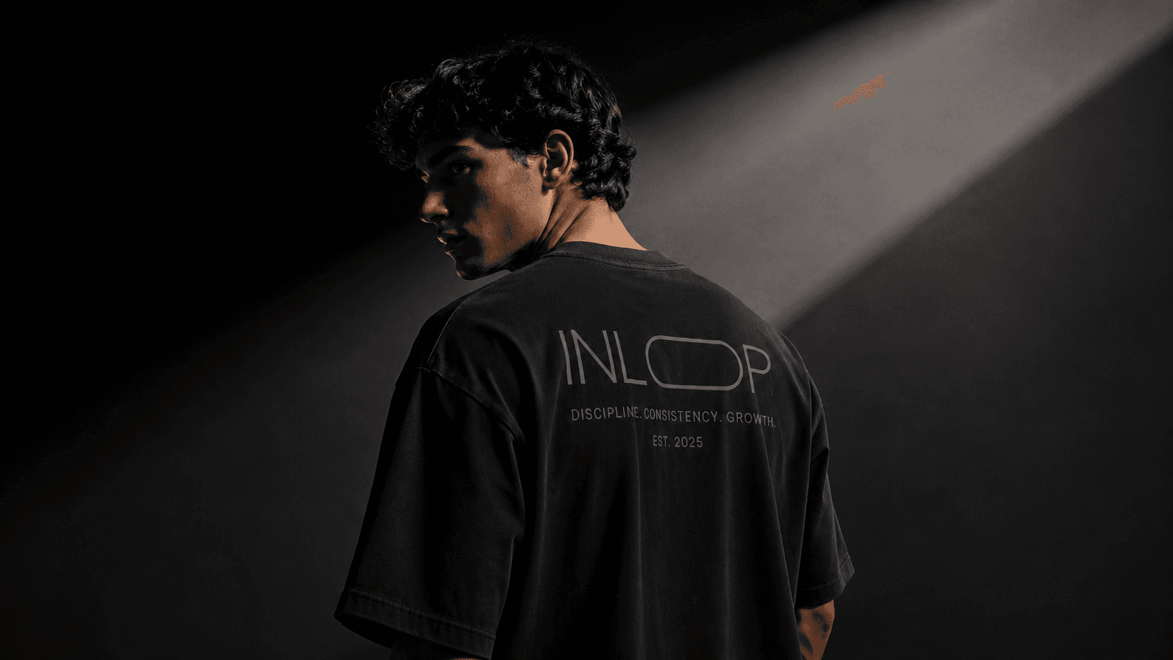 Model wearing black INLOOP streetwear under cinematic studio light
